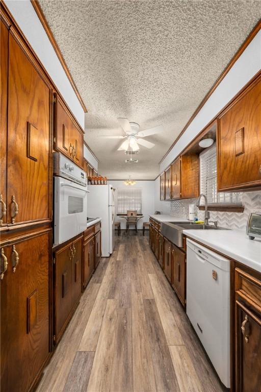 kitchen featuring ornamental molding, a textured ceiling, white appliances, ceiling fan, and light hardwood / wood-style flooring