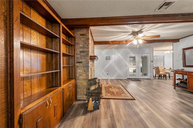 living room with wood-type flooring, a textured ceiling, french doors, and beam ceiling