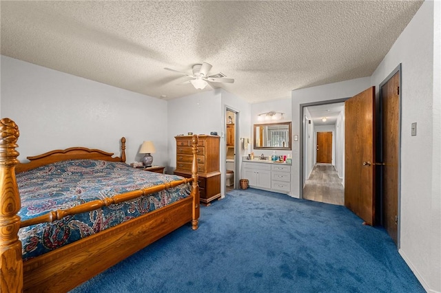 carpeted bedroom with a textured ceiling, ensuite bath, ceiling fan, and sink