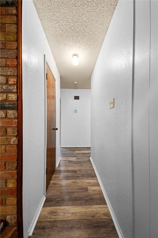 hallway featuring dark wood-type flooring and a textured ceiling