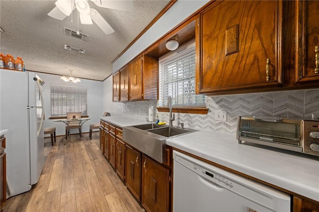 kitchen with sink, light hardwood / wood-style flooring, a textured ceiling, white appliances, and decorative backsplash