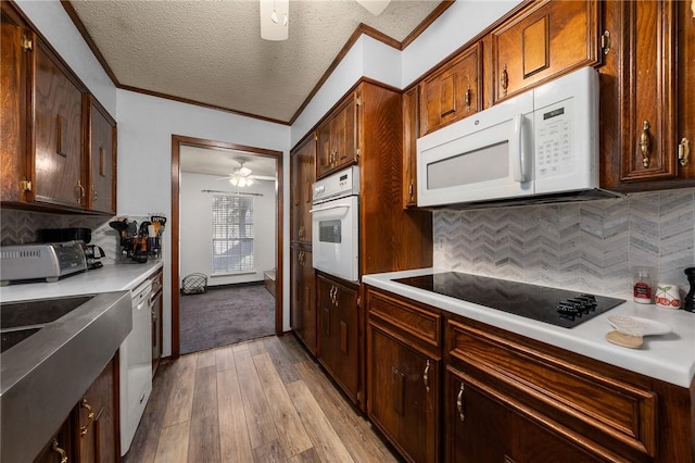 kitchen featuring light wood-type flooring, a textured ceiling, white appliances, and decorative backsplash