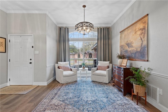 living area featuring ornamental molding, hardwood / wood-style floors, and a notable chandelier