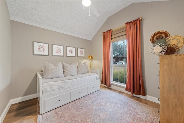 bedroom with ceiling fan, wood-type flooring, vaulted ceiling, and a textured ceiling