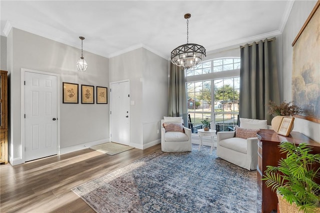 sitting room with crown molding, wood-type flooring, and a chandelier