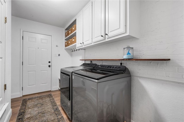 laundry area featuring dark wood-type flooring, cabinets, and washing machine and clothes dryer