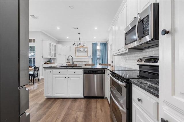 kitchen with pendant lighting, sink, appliances with stainless steel finishes, white cabinetry, and kitchen peninsula