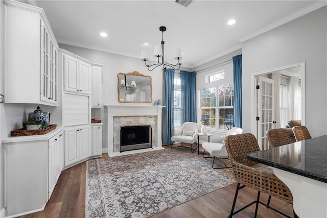 living room featuring a tile fireplace, crown molding, dark hardwood / wood-style floors, and an inviting chandelier