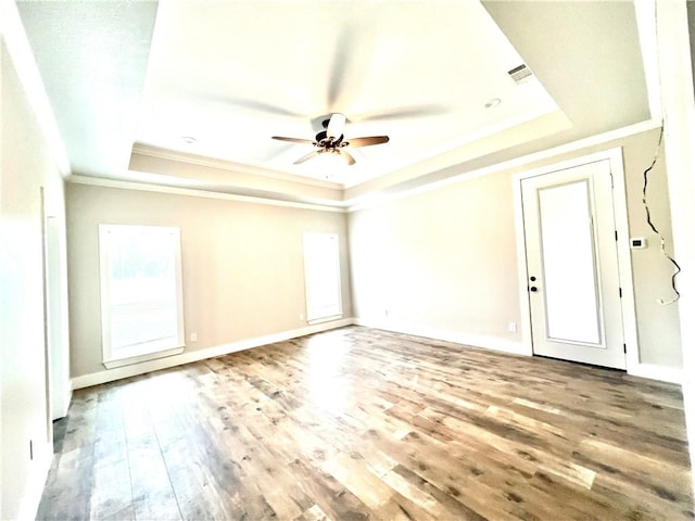 empty room with hardwood / wood-style floors, a raised ceiling, ceiling fan, and crown molding