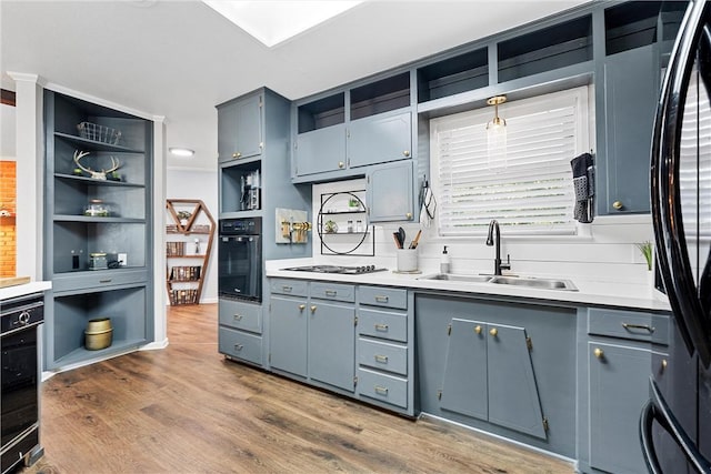 kitchen featuring gas cooktop, sink, hardwood / wood-style flooring, oven, and fridge