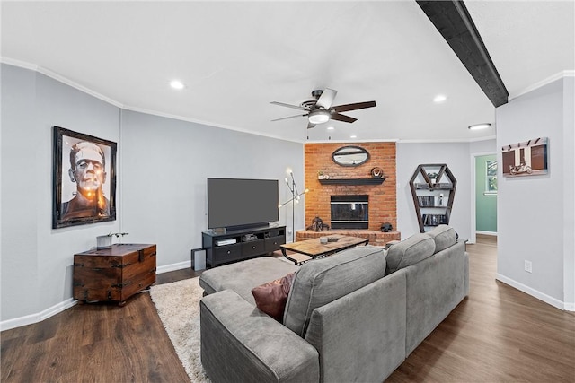 living room featuring beam ceiling, ceiling fan, dark wood-type flooring, crown molding, and a fireplace