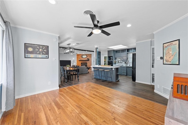 living room featuring ceiling fan, wood-type flooring, and ornamental molding