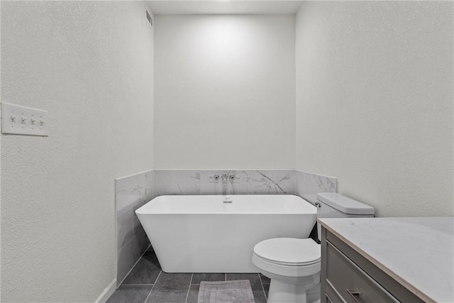 bathroom with toilet, tile walls, vanity, a bath, and tile patterned flooring