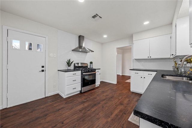 kitchen with sink, white cabinetry, backsplash, stainless steel gas range oven, and wall chimney exhaust hood