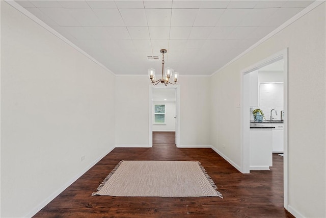 unfurnished dining area featuring crown molding, dark wood-type flooring, sink, and a chandelier