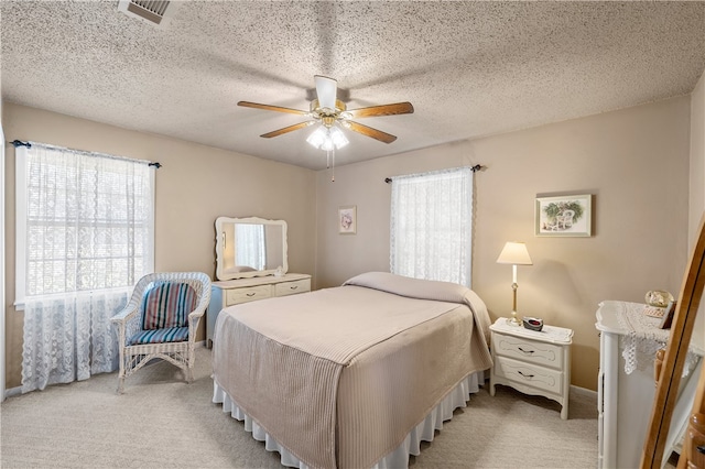 bedroom featuring ceiling fan, light colored carpet, and a textured ceiling