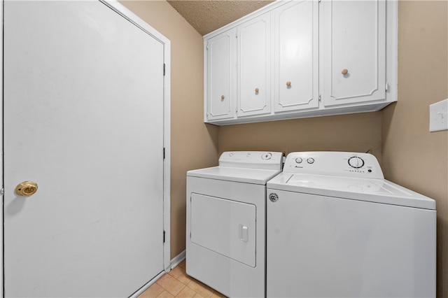 laundry room featuring cabinets, washing machine and clothes dryer, and a textured ceiling