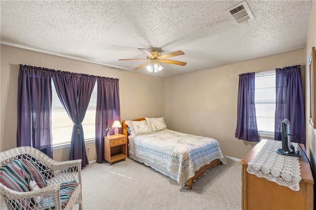 carpeted bedroom with multiple windows, a textured ceiling, and ceiling fan