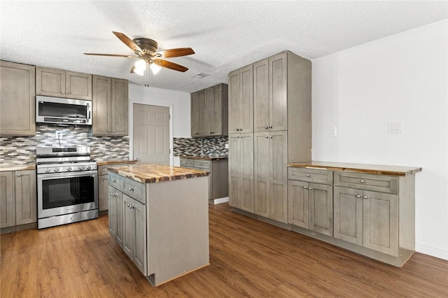 kitchen with hardwood / wood-style flooring, appliances with stainless steel finishes, a center island, and wooden counters