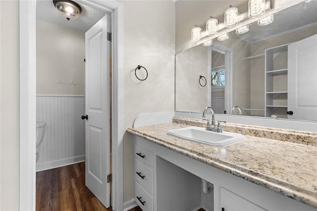 bathroom featuring hardwood / wood-style flooring, vanity, toilet, and a textured ceiling