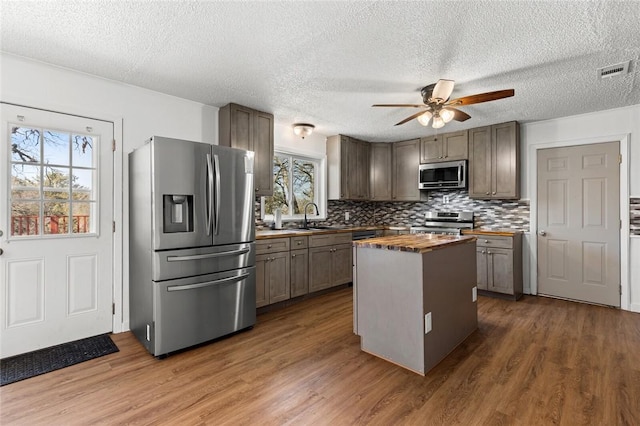 kitchen featuring a kitchen island, butcher block counters, sink, stainless steel appliances, and dark wood-type flooring