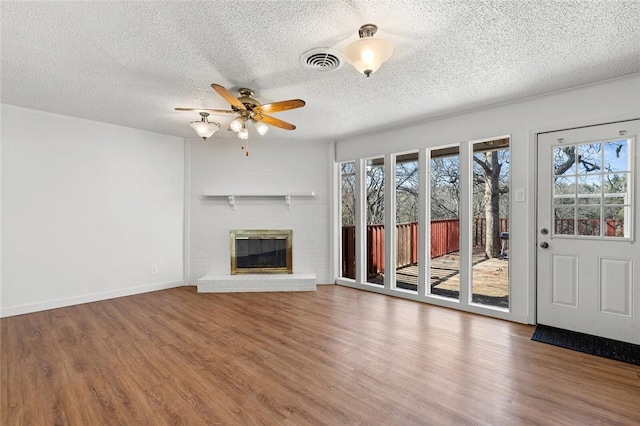 unfurnished living room featuring hardwood / wood-style floors, a textured ceiling, a fireplace, and ceiling fan