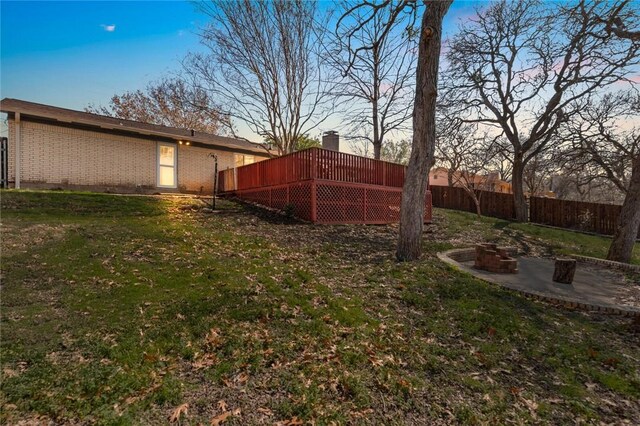 yard at dusk with a wooden deck and an outdoor fire pit