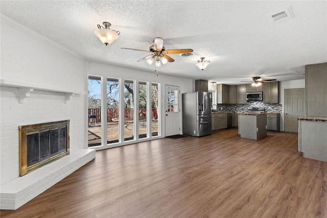 kitchen featuring a fireplace, dark wood-type flooring, stainless steel appliances, and a center island