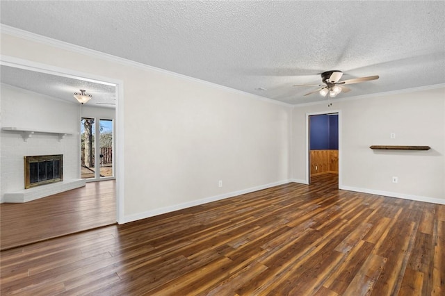 unfurnished living room with ornamental molding, ceiling fan, a brick fireplace, dark wood-type flooring, and a textured ceiling