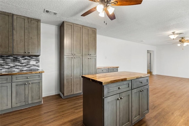 kitchen featuring gray cabinets, hardwood / wood-style floors, tasteful backsplash, butcher block counters, and ceiling fan