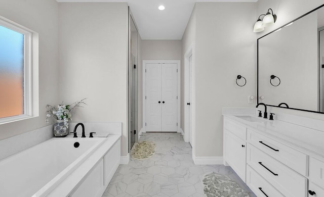 full bath featuring vanity, a garden tub, baseboards, and a closet