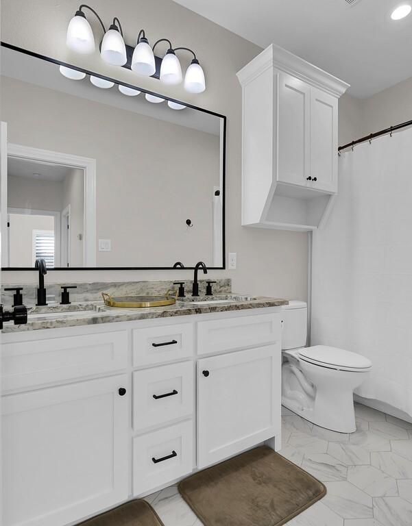 full bath featuring toilet, marble finish floor, and a sink