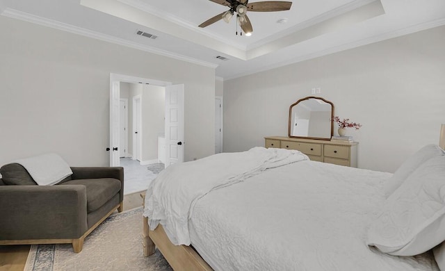 bedroom featuring a tray ceiling, visible vents, ceiling fan, and crown molding