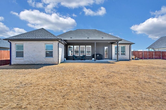 back of property featuring a patio area, a yard, fence, and roof with shingles