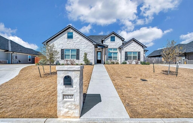 french provincial home featuring stone siding and fence