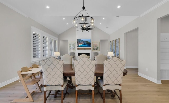 dining space featuring light wood finished floors, a chandelier, baseboards, and vaulted ceiling