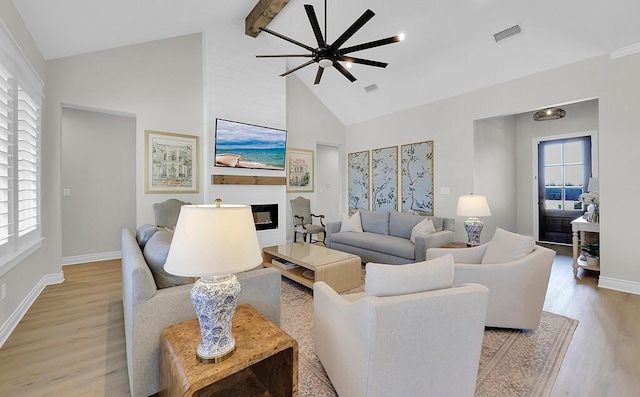 living room featuring light wood-type flooring, visible vents, plenty of natural light, and a glass covered fireplace