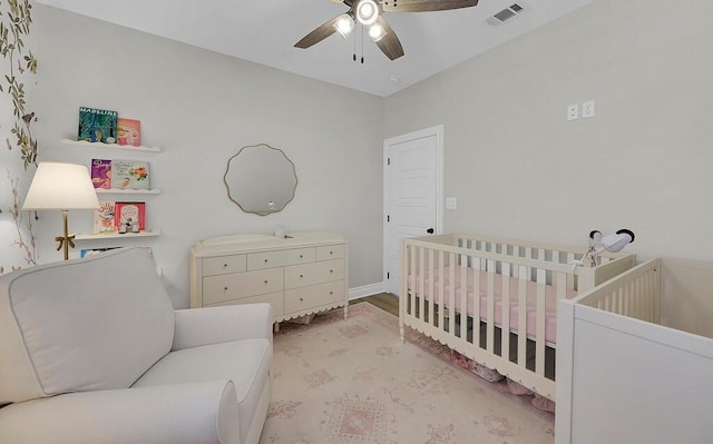 bedroom with visible vents, a ceiling fan, and a nursery area