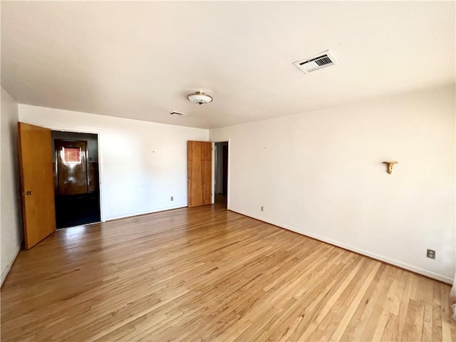 unfurnished room featuring light wood-style flooring, visible vents, and baseboards