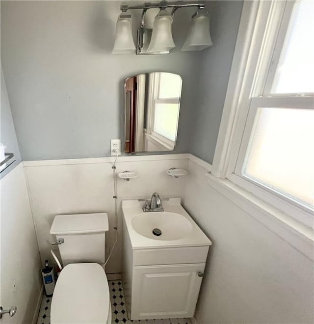 half bathroom featuring plenty of natural light, vanity, and toilet