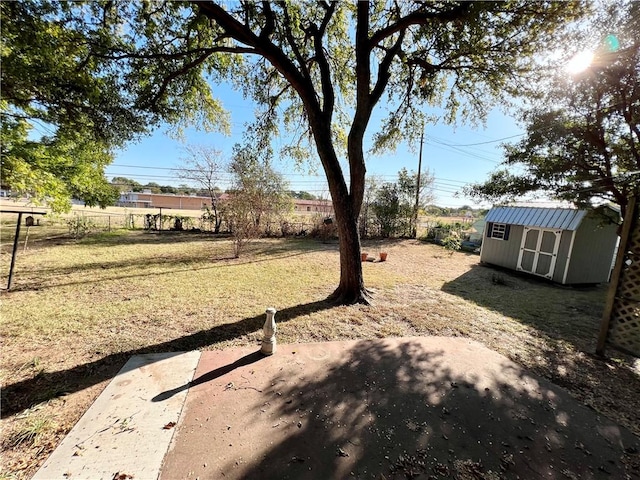 view of yard featuring a storage shed, fence, and an outdoor structure