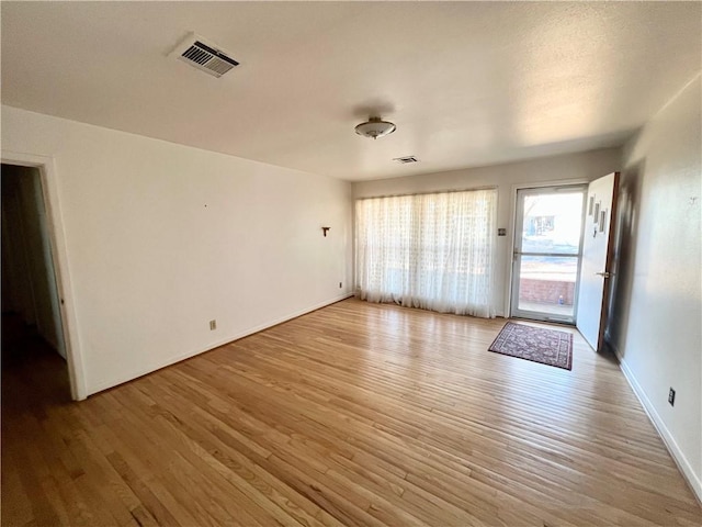 unfurnished living room with light wood-style flooring, visible vents, and baseboards