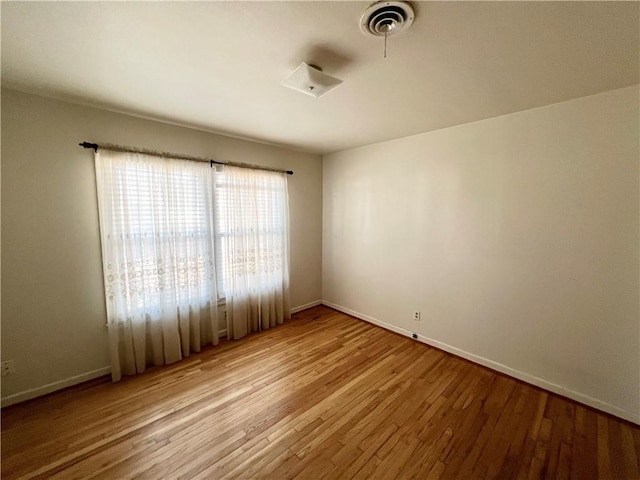 unfurnished room featuring light wood finished floors, baseboards, and visible vents