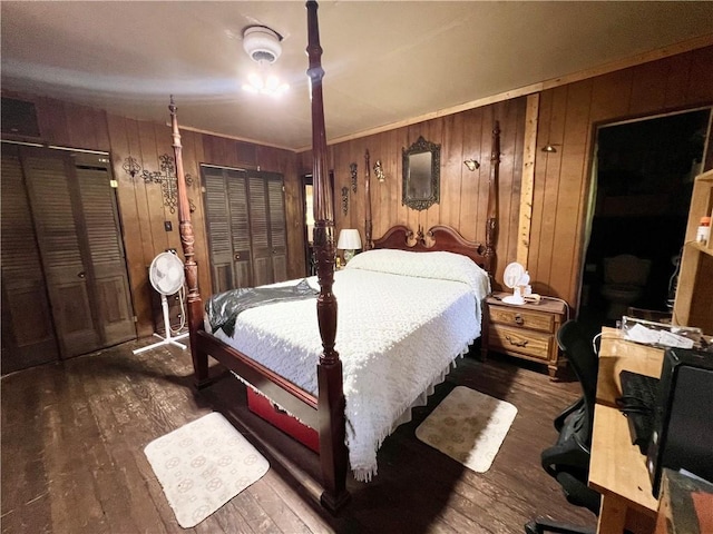 bedroom with dark wood-type flooring, crown molding, and wooden walls