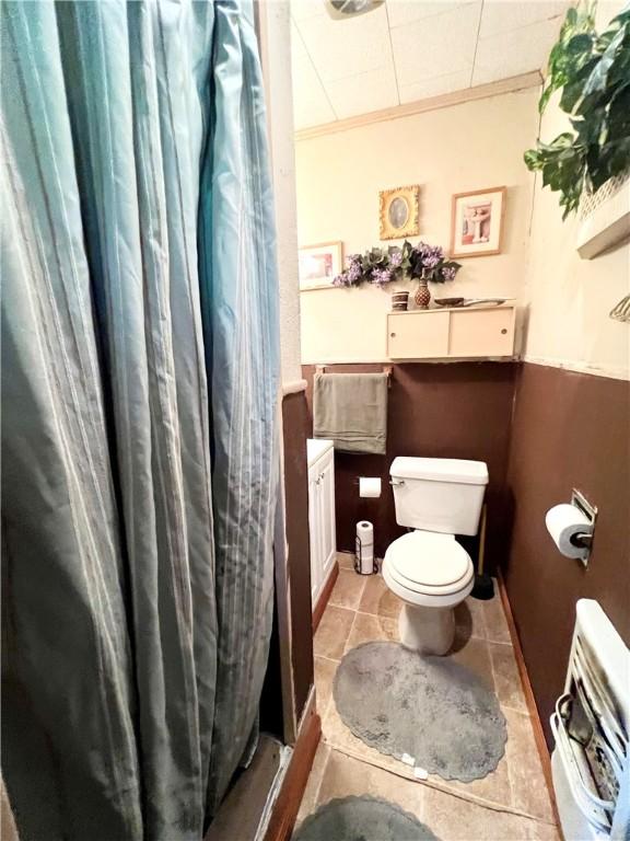 bathroom featuring curtained shower, tile patterned flooring, ornamental molding, and toilet