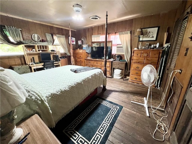 bedroom with wooden walls and dark hardwood / wood-style flooring