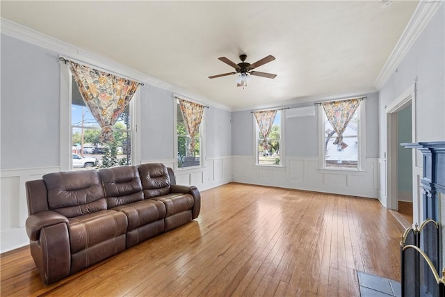 living room with a wall mounted air conditioner, hardwood / wood-style flooring, ceiling fan, and ornamental molding