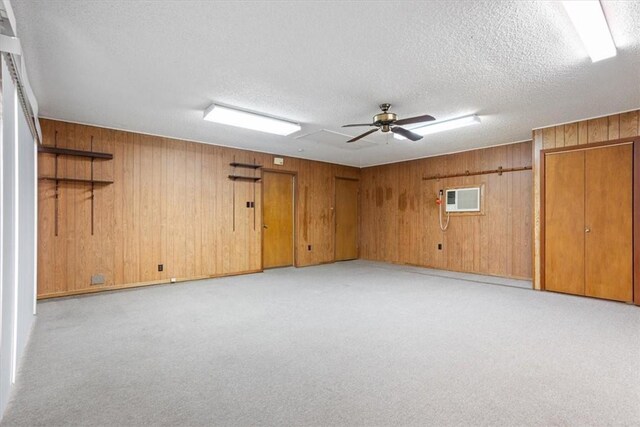 carpeted empty room with a wall mounted air conditioner, a textured ceiling, and wooden walls