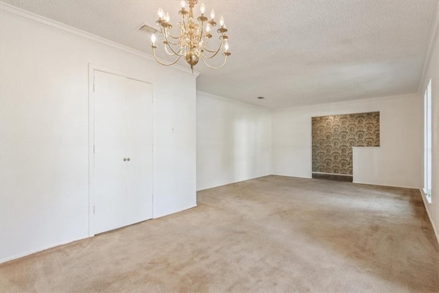 carpeted empty room with a textured ceiling, an inviting chandelier, and ornamental molding