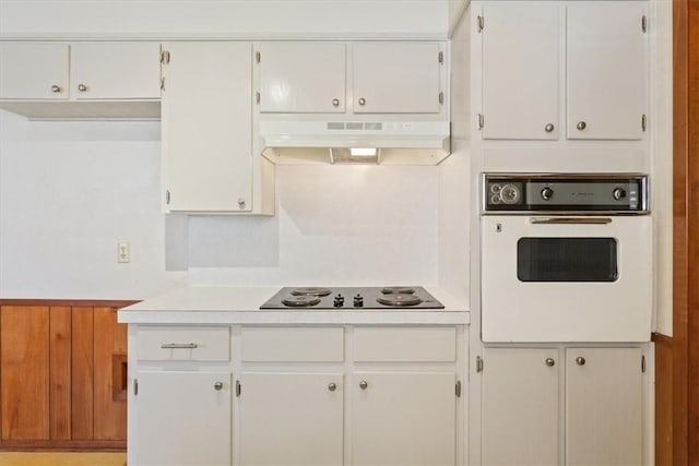 kitchen featuring white cabinets, wooden walls, black electric cooktop, and oven